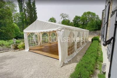 Façade d'un grand bâtiment ancien entouré de motos stationnées sur une pelouse et une allée gravillonnée.