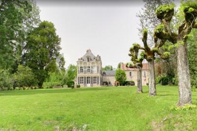 Façade d'un grand bâtiment ancien entouré de motos stationnées sur une pelouse et une allée gravillonnée.