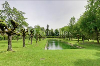 Façade d'un grand bâtiment ancien entouré de motos stationnées sur une pelouse et une allée gravillonnée.