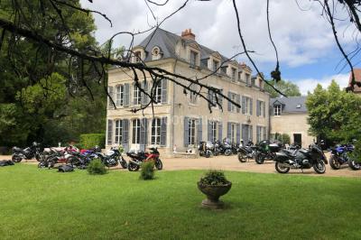 Façade d'un grand bâtiment ancien entouré de motos stationnées sur une pelouse et une allée gravillonnée.
