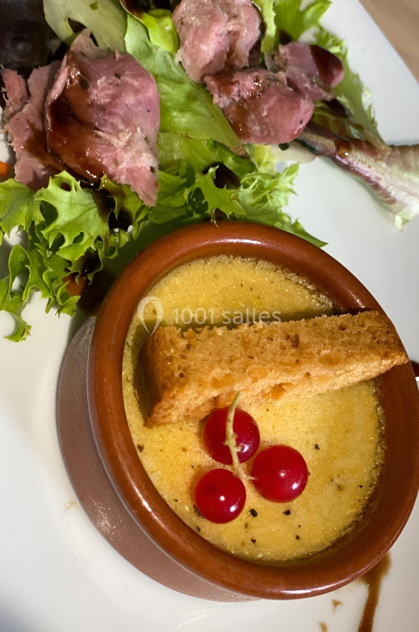 Crème brûlée servie avec un croûton, des groseilles et une salade verte accompagnée de tranches de viande.