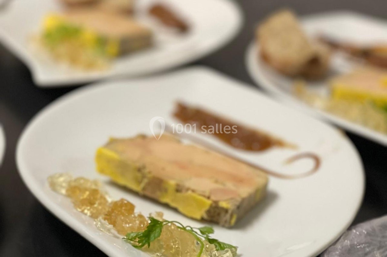 Assiette de foie gras accompagné de gelée, d'une sauce brune et de pain, présenté sur une table.