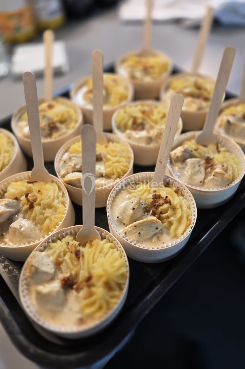 Petits plats individuels contenant purée, morceaux de viande en sauce et cuillères en bois, disposés sur un plateau.