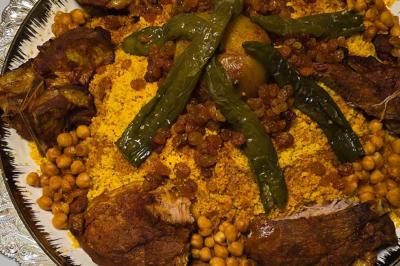 Assiette garnie d'un jarret d'agneau en sauce, accompagnée de légumes, fruits confits et d'une décoration en œuf et cerise.