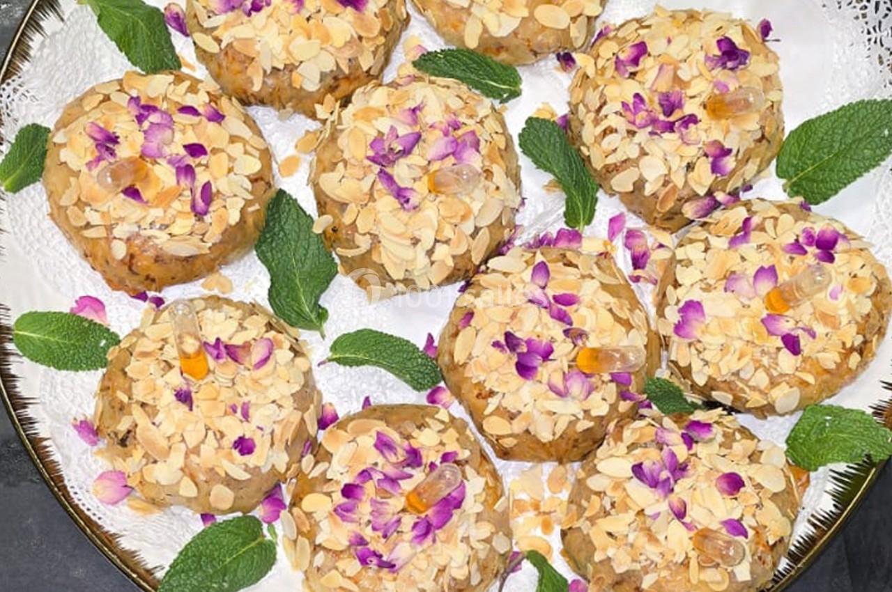Assortiment de biscuits garnis d'amandes effilées, de fleurs comestibles et décorés de feuilles de menthe.