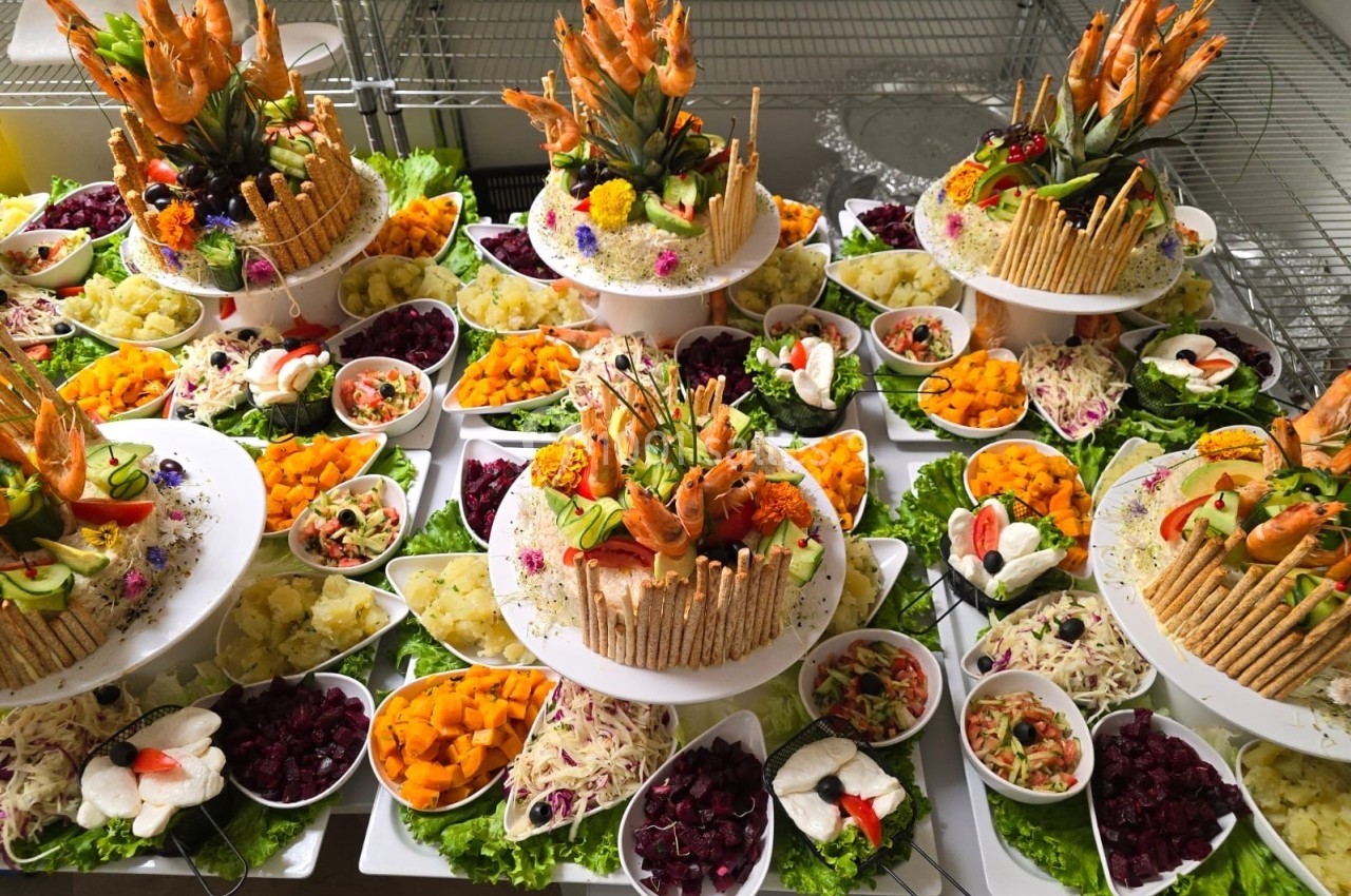 Plateau de buffet garni de légumes, fruits, crevettes et décorations comestibles, disposé sur plusieurs étages.