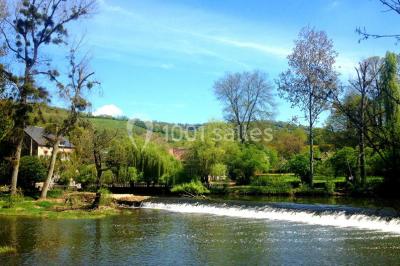 Salle de bain moderne avec carrelage gris, lavabo, toilettes et fenêtre laissant entrer la lumière naturelle.