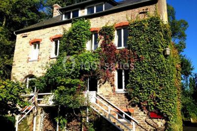 Salle de bain moderne avec carrelage gris, lavabo, toilettes et fenêtre laissant entrer la lumière naturelle.