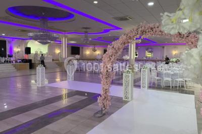 Salle de réception décorée avec tables dressées, compositions florales, buffet, plats servis et pièce montée.