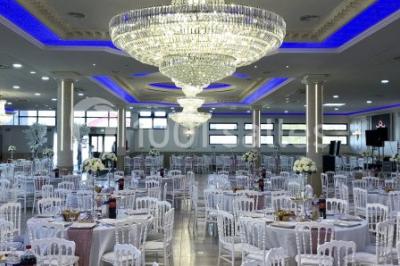 Salle de réception décorée avec tables dressées, compositions florales, buffet, plats servis et pièce montée.