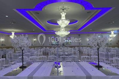 Salle de réception décorée avec tables dressées, compositions florales, buffet, plats servis et pièce montée.
