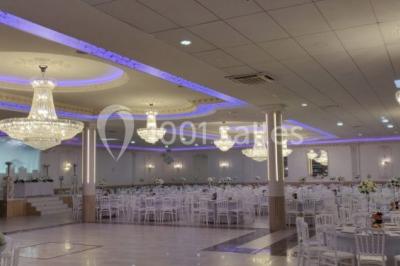 Salle de réception décorée avec tables dressées, compositions florales, buffet, plats servis et pièce montée.