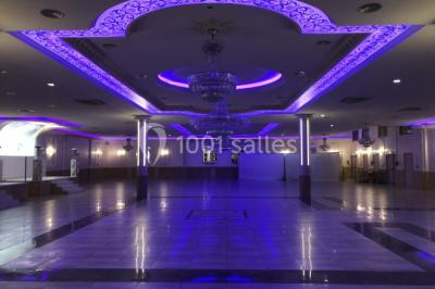 Salle de réception décorée avec tables dressées, compositions florales, buffet, plats servis et pièce montée.