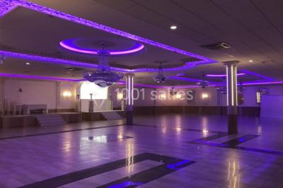 Salle de réception décorée avec tables dressées, compositions florales, buffet, plats servis et pièce montée.