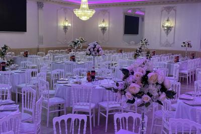 Salle de réception décorée avec tables dressées, compositions florales, buffet, plats servis et pièce montée.