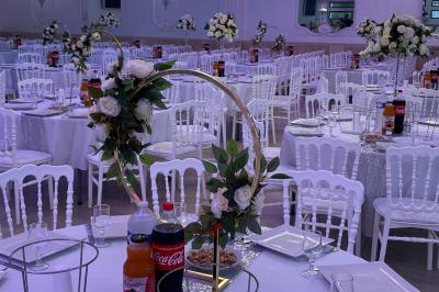 Salle de réception décorée avec tables dressées, compositions florales, buffet, plats servis et pièce montée.