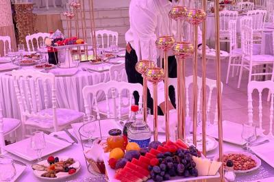 Salle de réception décorée avec tables dressées, compositions florales, buffet, plats servis et pièce montée.