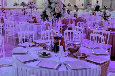Salle de réception décorée avec tables dressées, compositions florales, buffet, plats servis et pièce montée.