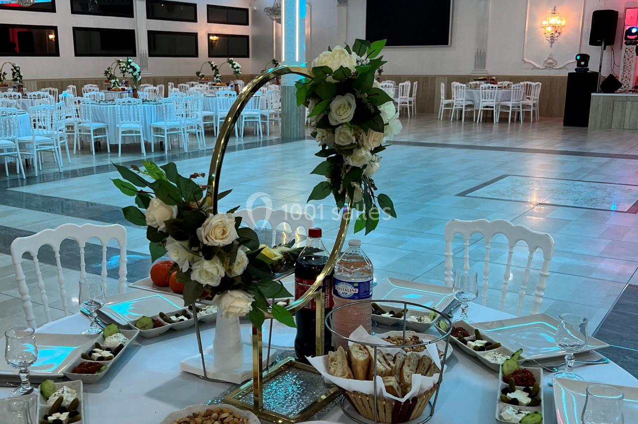 Table élégamment dressée avec des assiettes, des entrées variées et une décoration florale dans une salle de réception…