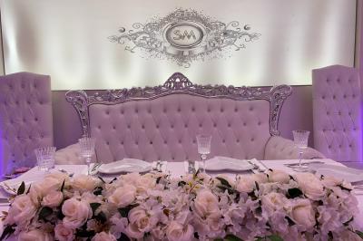 Salle de réception décorée avec tables dressées, compositions florales, buffet, plats servis et pièce montée.