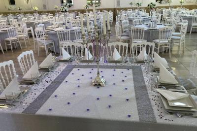 Salle de réception décorée avec tables dressées, compositions florales, buffet, plats servis et pièce montée.