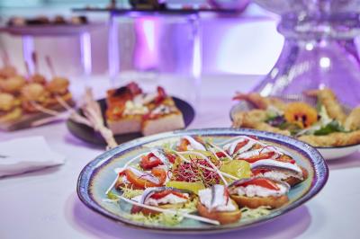 Salle de réception avec tables dressées, verres alignés au premier plan et décorations florales en arrière-plan.