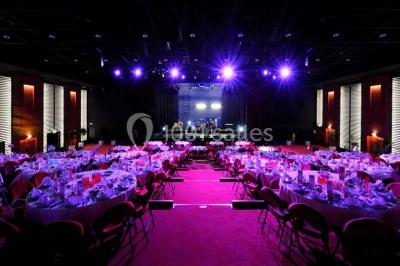 Salle avec structures gonflables colorées, tables, chaises et stands installés pour un événement intérieur.