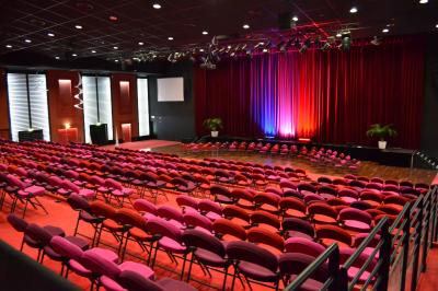 Salle avec structures gonflables colorées, tables, chaises et stands installés pour un événement intérieur.