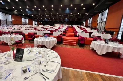 Salle avec structures gonflables colorées, tables, chaises et stands installés pour un événement intérieur.