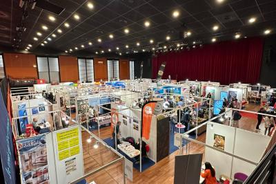 Salle avec structures gonflables colorées, tables, chaises et stands installés pour un événement intérieur.