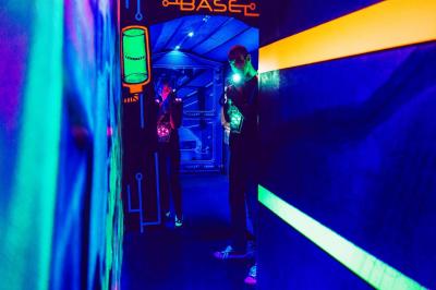 Équipements de laser game accrochés à un mur, éclairés par des lumières rouges et vertes.