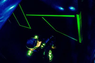 Équipements de laser game accrochés à un mur, éclairés par des lumières rouges et vertes.