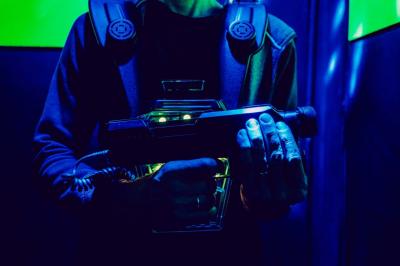 Équipements de laser game accrochés à un mur, éclairés par des lumières rouges et vertes.