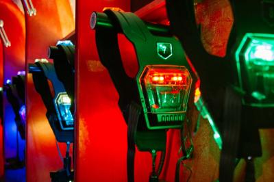Équipements de laser game accrochés à un mur, éclairés par des lumières rouges et vertes.