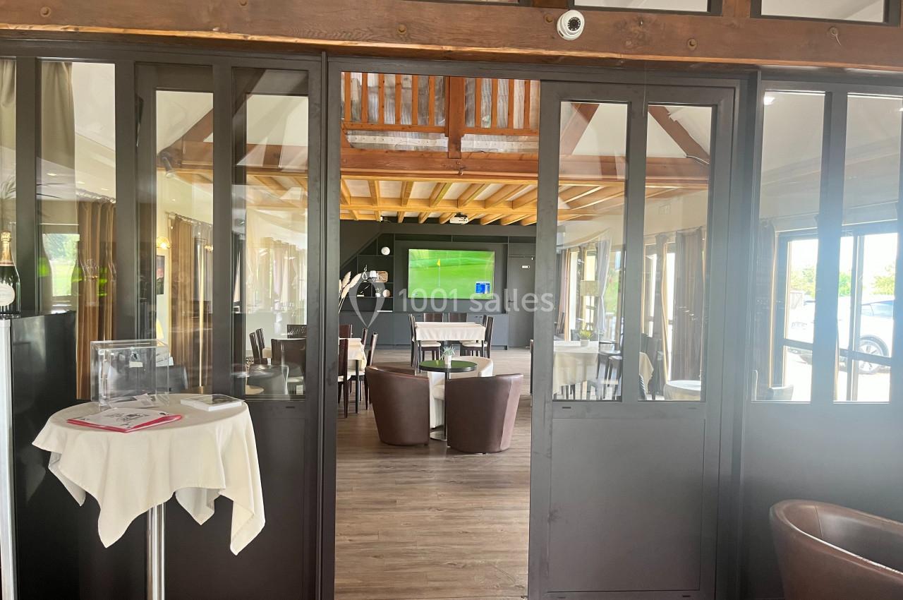 Salle lumineuse avec des fauteuils en cuir, une table dressée et un écran diffusant un programme à l'arrière-plan.