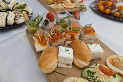 Plateau de canapés variés avec mini-sandwichs, toasts garnis et brochettes, disposé sur une table blanche.