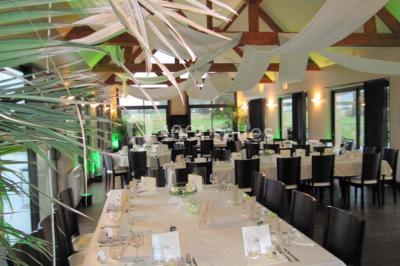 Salle de restaurant décorée avec des nappes blanches et rouges, éclairage tamisé et ambiance chaleureuse.