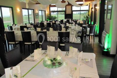 Salle de restaurant décorée avec des nappes blanches et rouges, éclairage tamisé et ambiance chaleureuse.