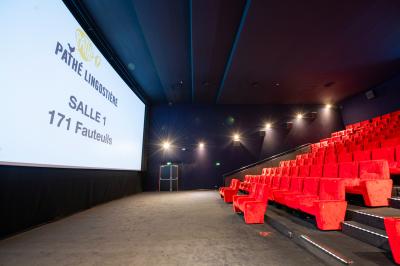 Miniature Location salle Nice (Alpes-Maritimes) - Pathé Lingostiere #5 Salle de cinéma vide avec des rangées de fauteuils rouges et un écran illuminé en arrière-plan.