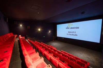 Miniature Location salle Nice (Alpes-Maritimes) - Pathé Lingostiere #9 Salle de cinéma vide avec des rangées de fauteuils rouges et un écran illuminé en arrière-plan.