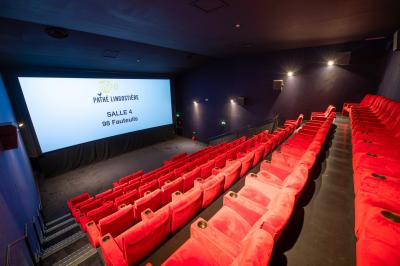 Miniature Location salle Nice (Alpes-Maritimes) - Pathé Lingostiere #11 Salle de cinéma vide avec des rangées de fauteuils rouges et un écran illuminé en arrière-plan.