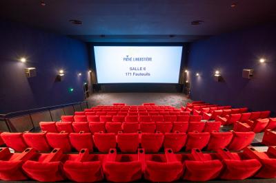 Miniature Location salle Nice (Alpes-Maritimes) - Pathé Lingostiere #13 Salle de cinéma vide avec des rangées de fauteuils rouges et un écran illuminé en arrière-plan.
