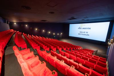Miniature Location salle Nice (Alpes-Maritimes) - Pathé Lingostiere #14 Salle de cinéma vide avec des rangées de fauteuils rouges et un écran illuminé en arrière-plan.