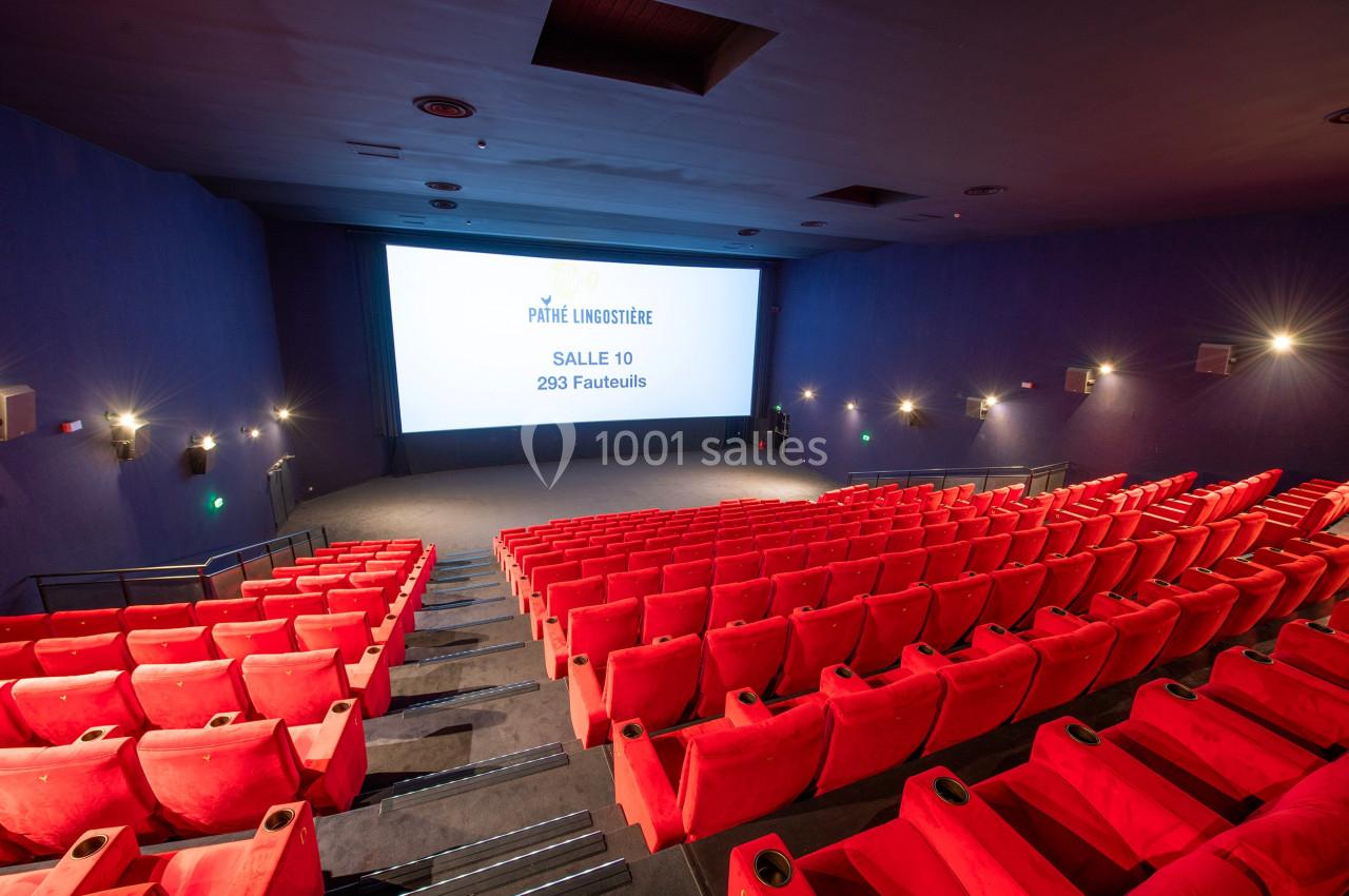 Salle de cinéma vide avec des rangées de fauteuils rouges et un écran affichant des informations sur la salle.