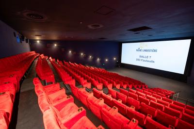 Miniature Location salle Nice (Alpes-Maritimes) - Pathé Lingostiere #17 Salle de cinéma vide avec des rangées de fauteuils rouges et un écran illuminé en arrière-plan.