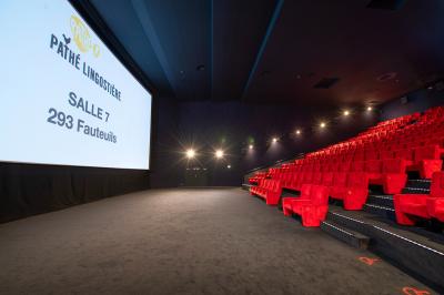 Miniature Location salle Nice (Alpes-Maritimes) - Pathé Lingostiere #3 Salle de cinéma vide avec des rangées de fauteuils rouges et un écran illuminé en arrière-plan.