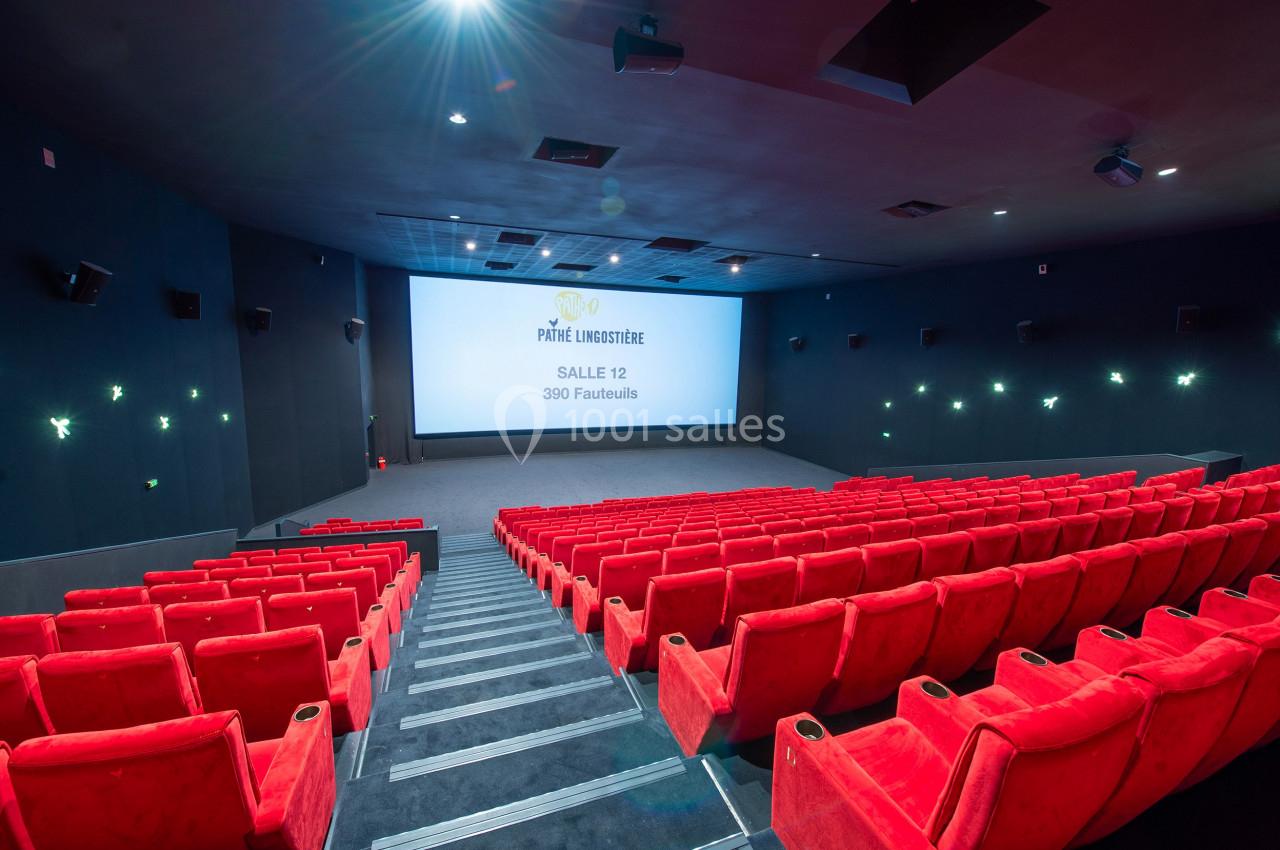 Salle de cinéma moderne avec rangées de sièges rouges vides et écran affichant ’Pathé Lumière, Salle 12, 390 fauteuils’.