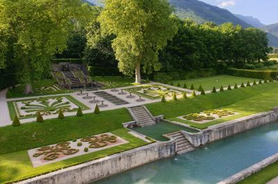 Fontaines jaillissantes devant des bâtiments historiques avec des montagnes enneigées en arrière-plan.