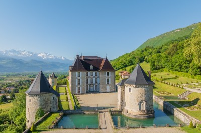 Salle élégante avec moulures, lustres, peintures anciennes et une table dressée avec verres et décorations florales.