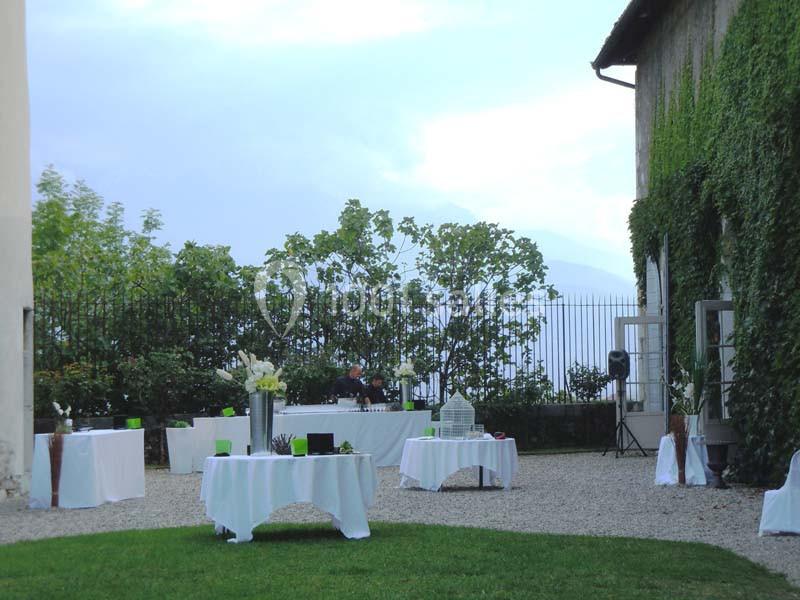 Cour extérieure avec des tables dressées pour un événement, entourée de verdure et de bâtiments recouverts de lierre.